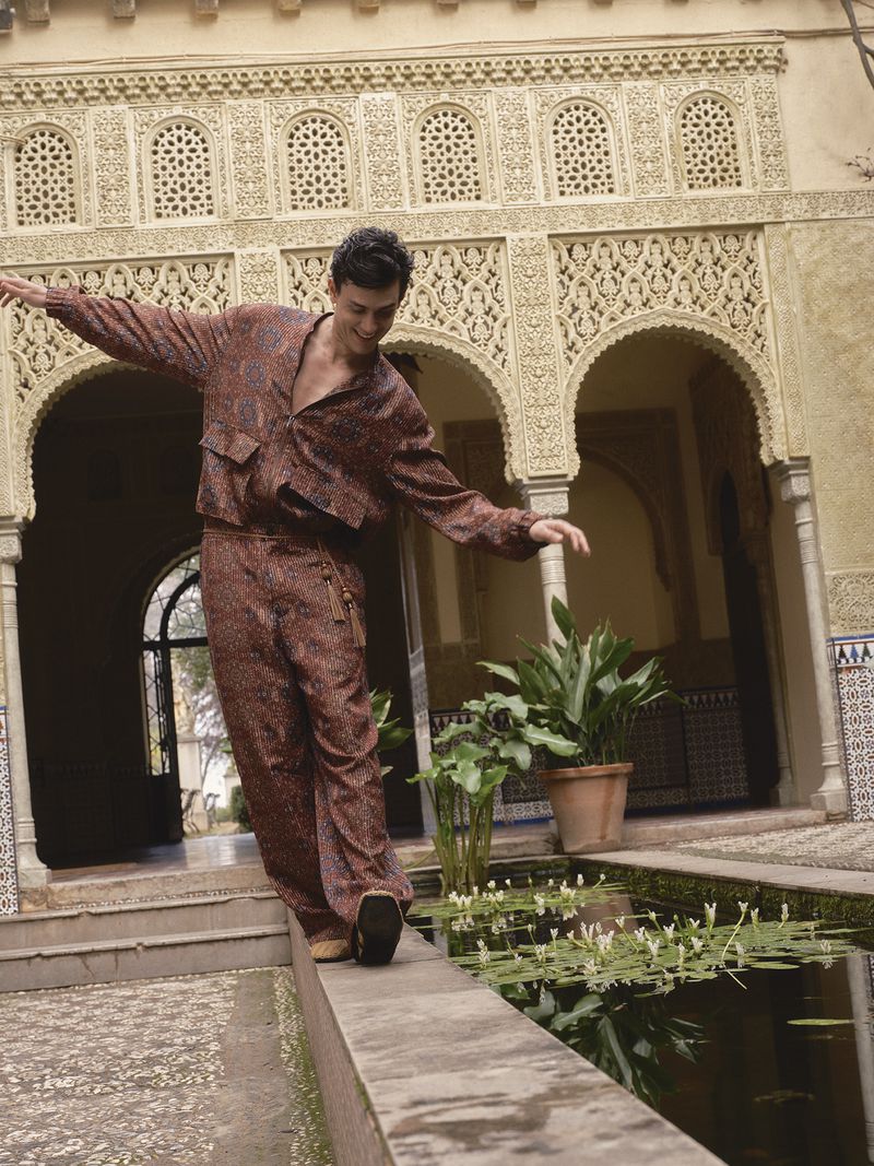 Xavier Serrano balances along a stone pool ledge wearing a patterned brown set in an ornate Moorish courtyard.