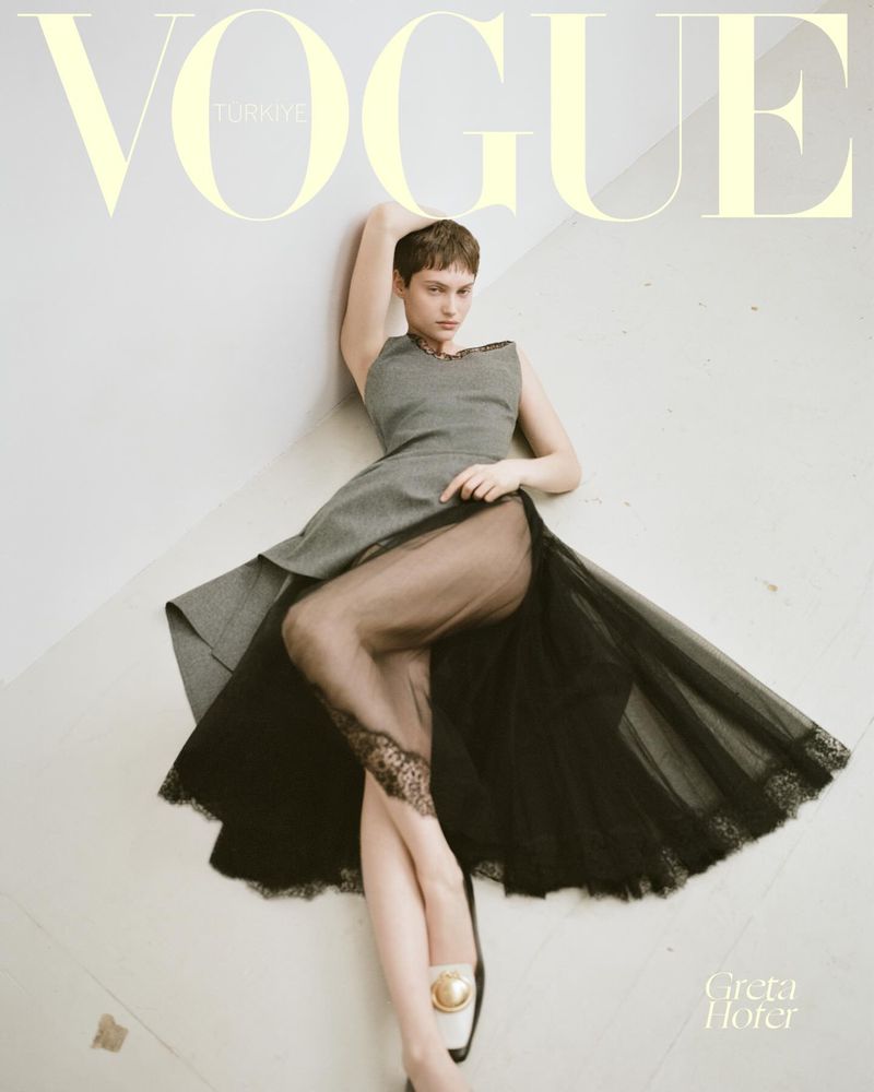 Model Greta Hofer wearing a grey sleeveless bodice with a sheer black tulle lace skirt reclining on a floor for Vogue Turkey.