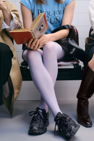 Young woman reads a book titled Pool for Fun while sitting in what appears to be a waiting room with other people nearby.