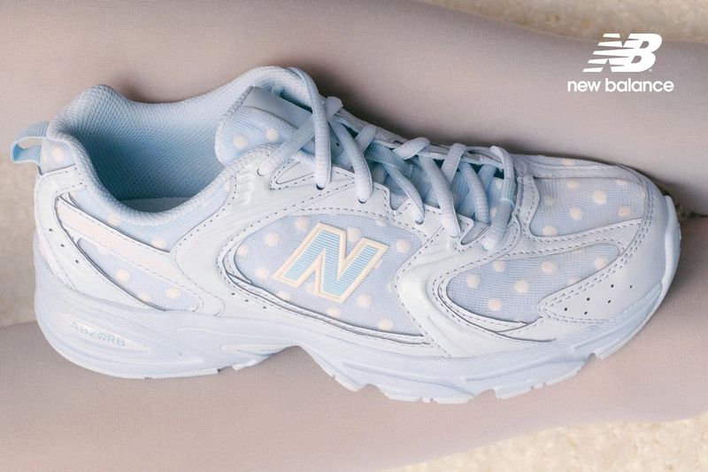 Close-up studio shot of a light blue New Balance sneaker with white polka dots and a light blue 'N' logo.