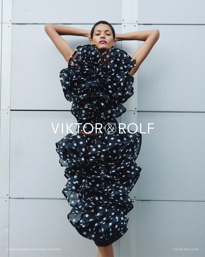Model Laiza de Moura posing in a voluminous black and white polka dot ruffled dress against a grey panelled wall for Viktor and Rolf.