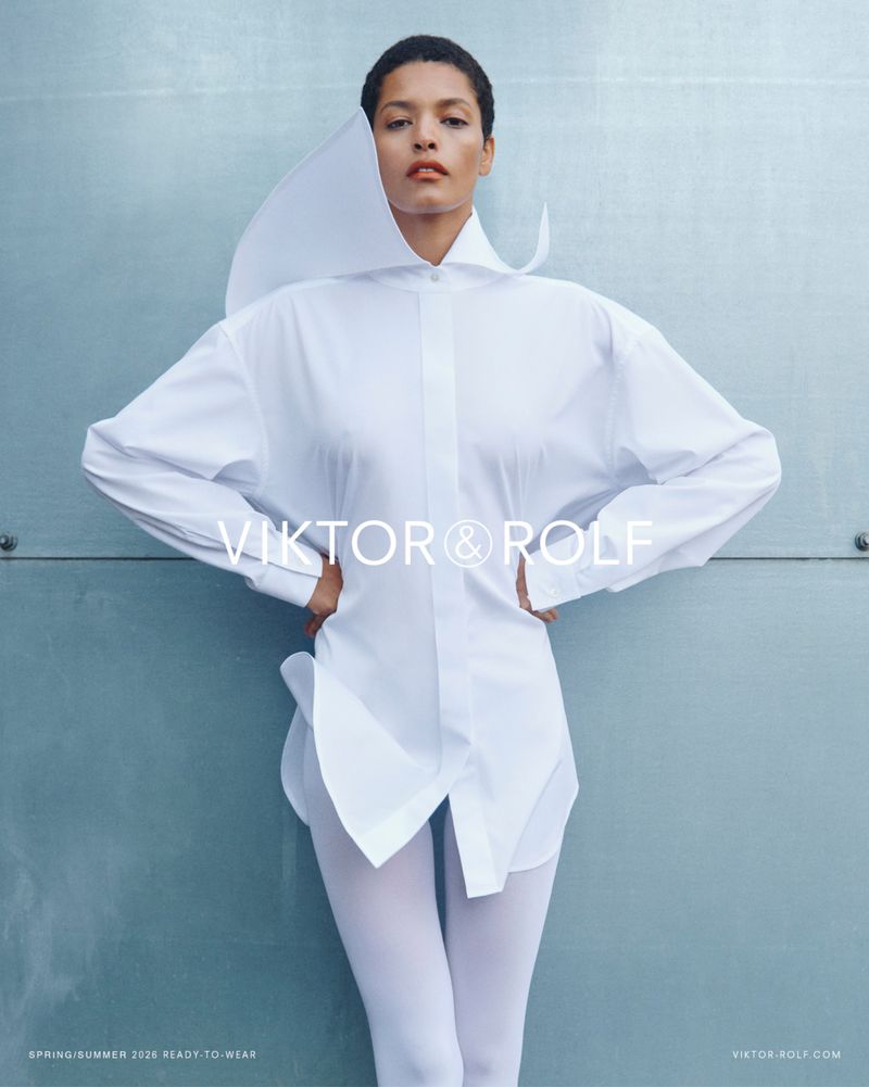Model Laiza de Moura wearing an architectural white button-down shirt and white tights against a soft pale blue panel backdrop.