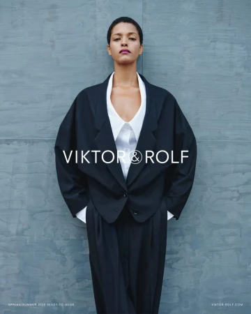 Model Laiza de Moura in an oversized black tailored jacket and white shirt against a textured grey wall for Viktor & Rolf.