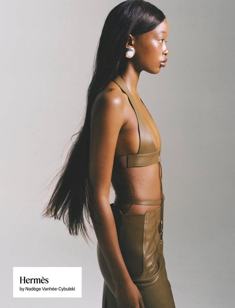 Black female model in profile wearing a brown leather halter top against a solid neutral background