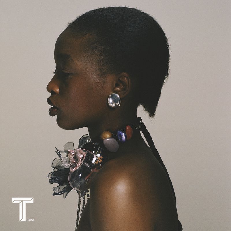 Side profile portrait of model Kethia Ngeleza wearing a sculptural statement necklace and silver disc earring against a neutral backdrop.