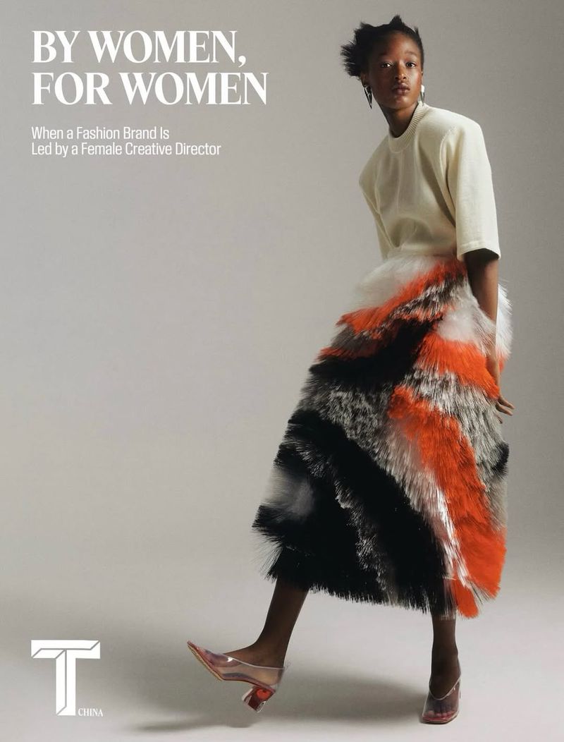 Model wearing a white top and a textured, multi-colored tiered skirt against a neutral seamless background.