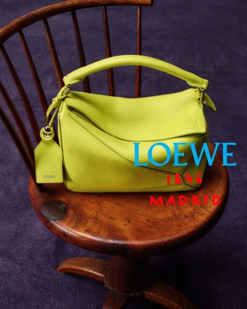 A vibrant lime yellow leather Loewe Puzzle handbag placed on a wooden spindle chair over a deep purple floor.