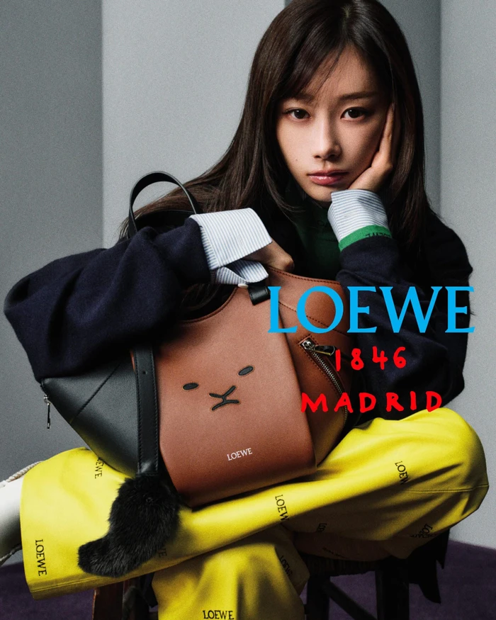 Giselle seated in yellow Loewe trousers holding a brown and black leather Loewe handbag for an advertising campaign.