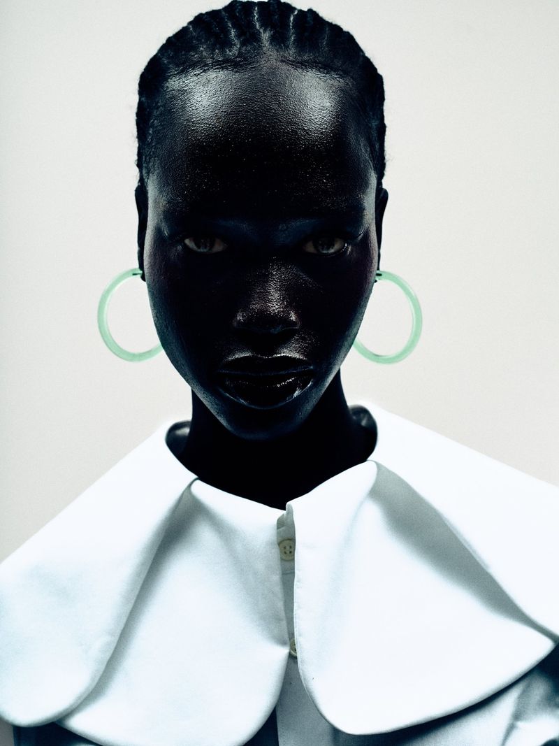 Close-up portrait of model Grace Ayup wearing circular mint hoop earrings and an oversized white collar against a light studio backdrop.