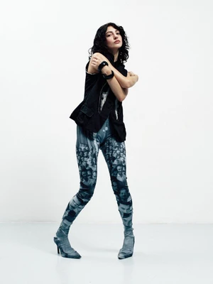 Model Grace Ayup poses in a black vest and photographic print leggings against a white studio background for Schön Magazine.