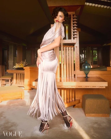 Zendaya poses in a pale fringed tassel dress and feathered stiletto heels in a warm wood-furnished architectural interior for Vogue Brasil.