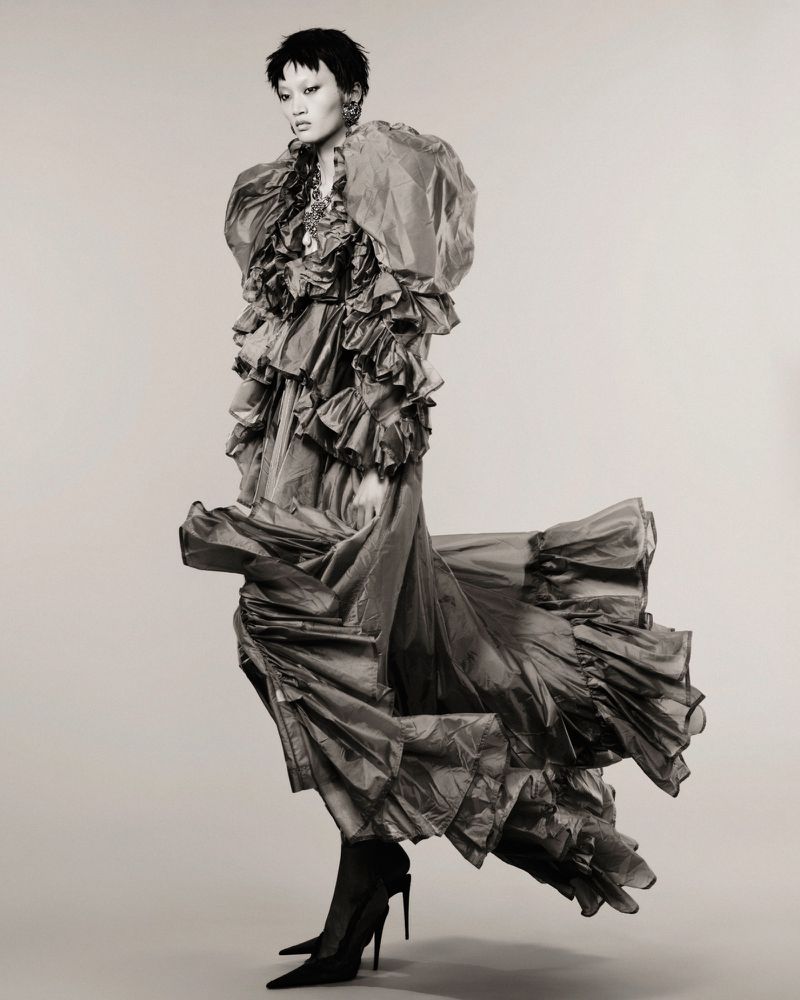 Model in a voluminous ruffled gown and black heels against a plain background for Numero Netherlands.