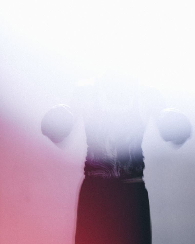 Motion-blurred silhouette of a figure in boxing gloves enveloped by high-key white light and soft red peripheral glow.