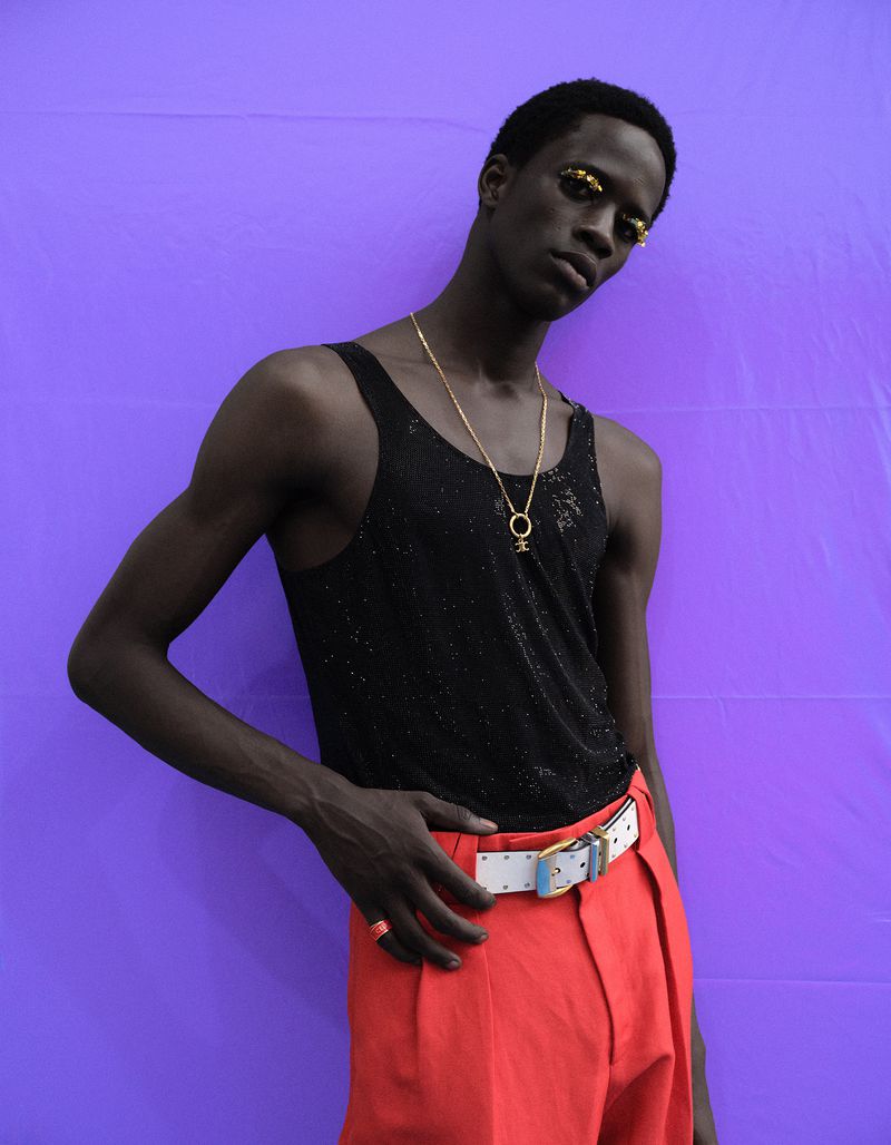Model in black tank top and red trousers with gold necklace against vivid purple background for Esquire China