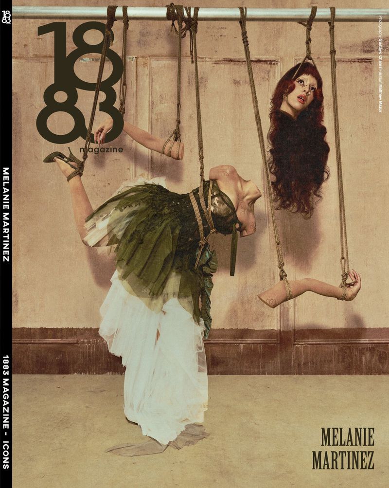 Melanie Martinez on 1883 Magazine cover with detached body parts suspended by ropes wearing an olive green and white gown.