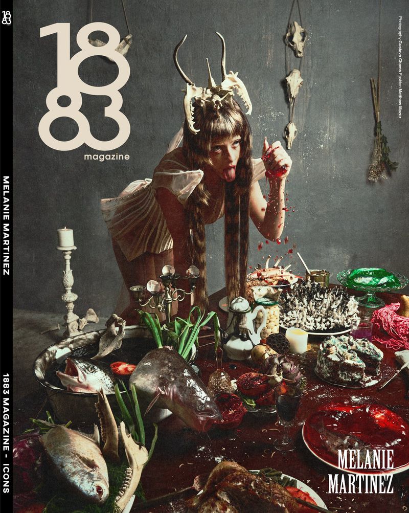 Melanie Martinez leaning over a feast table wearing an animal skull headdress for 1883 Magazine editorial cover
