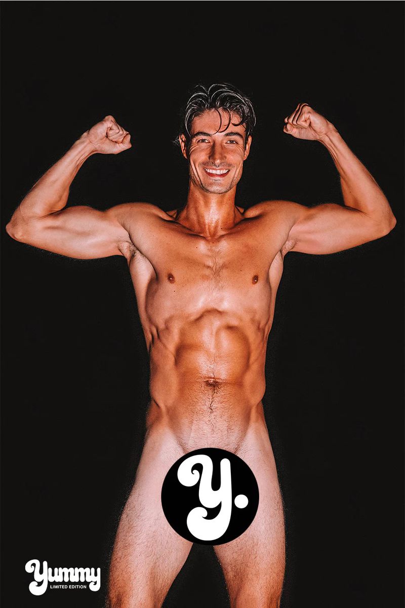 Muscular man smiling and posing with flexed biceps against a solid black seamless backdrop.