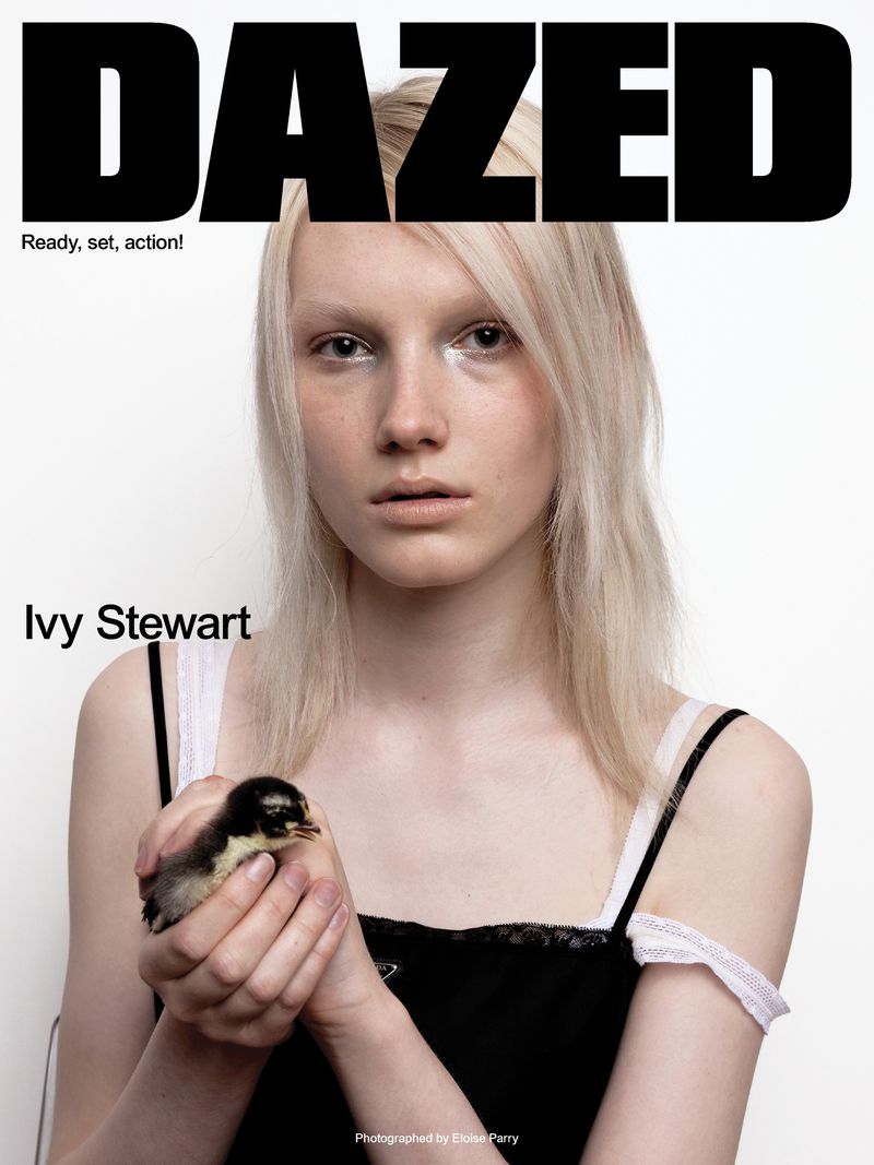 Model Ivy Stewart with platinum blonde hair holding a small duckling while wearing a black camisole against a white backdrop.