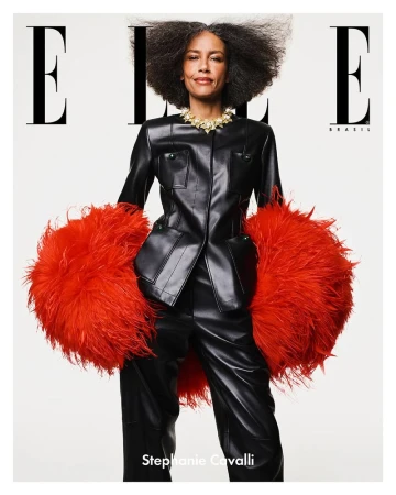Model Stephanie Cavalli posing in a black leather suit with oversized red feathered cuffs against a white background.