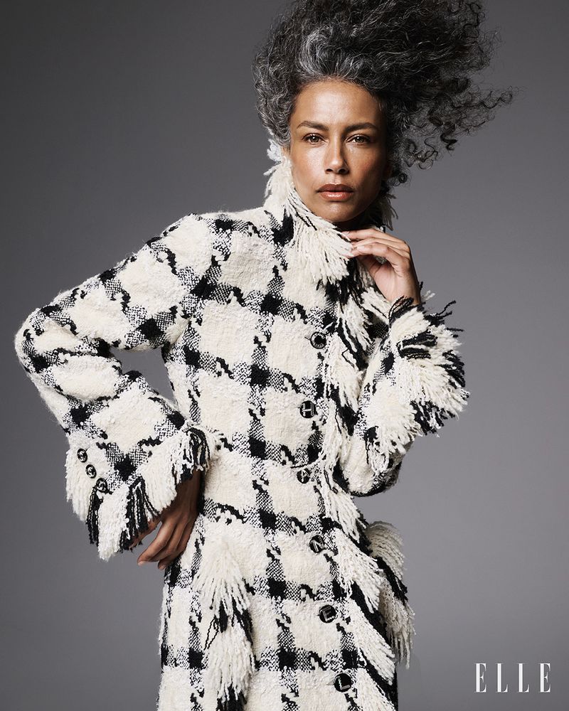 Stephanie Cavalli wearing a fringed black and white houndstooth tweed coat against a neutral studio backdrop for Elle Brasil.