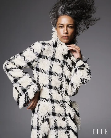 Stephanie Cavalli wearing a fringed black and white houndstooth tweed coat against a neutral studio backdrop for Elle Brasil.