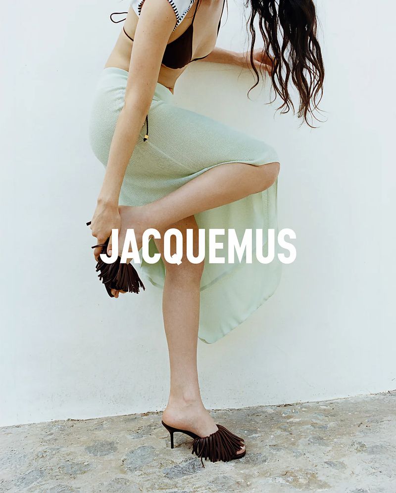 Model wearing a pale mint green maxi skirt and brown fringe kitten heel mules standing against a white wall.