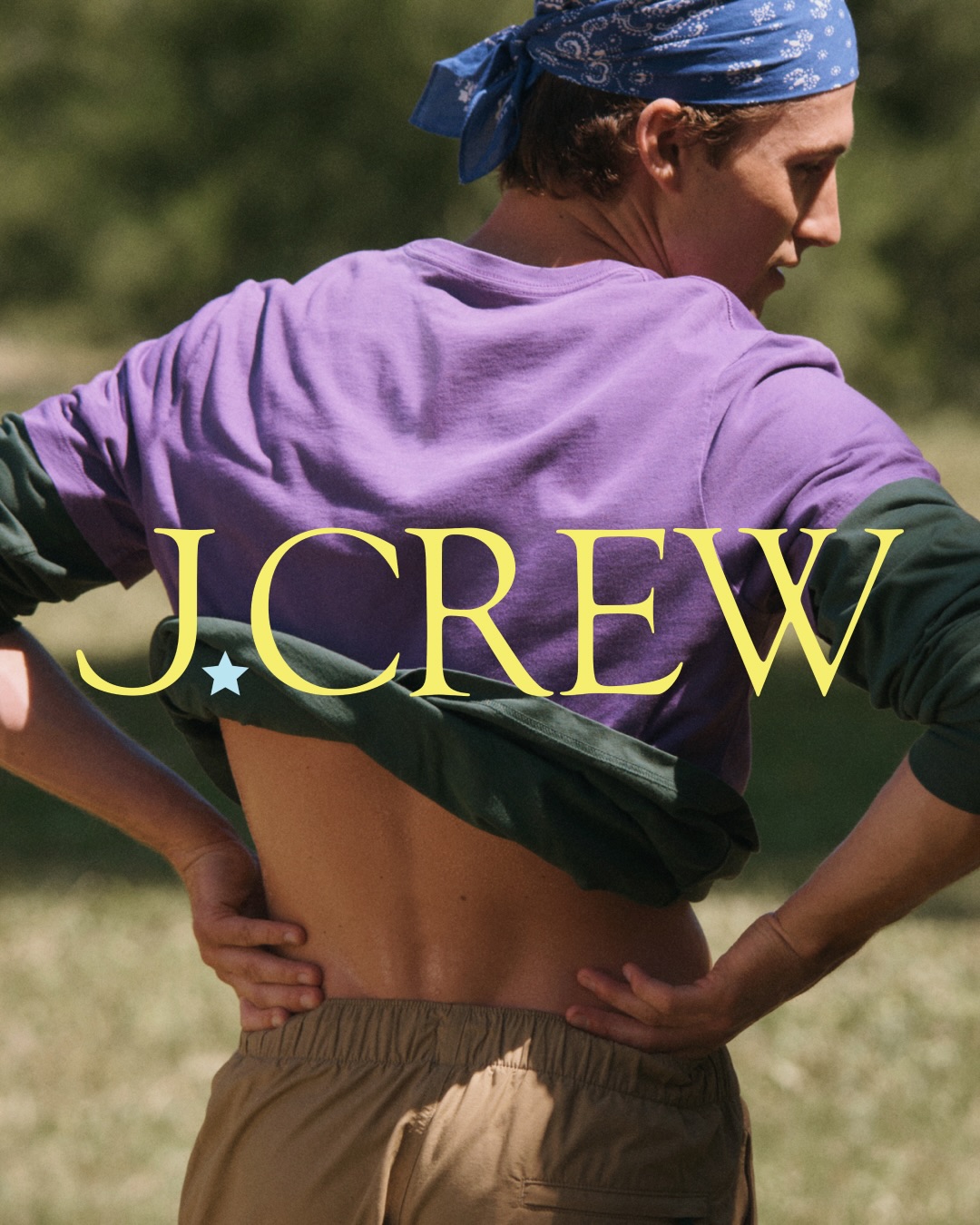Rear view of a model in a purple shirt, blue bandana, and khaki shorts outdoors for J. Crew Camp Crew campaign.