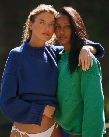 Two female models posing closely together wearing colourful knit sweaters for J. Crew Summer campaign