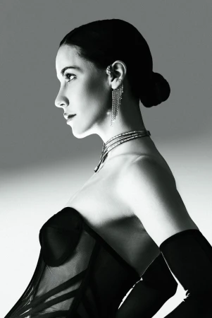 Monochrome profile portrait of model Anna Alimani wearing a black corset, opera gloves, and diamond jewelry against a studio backdrop.