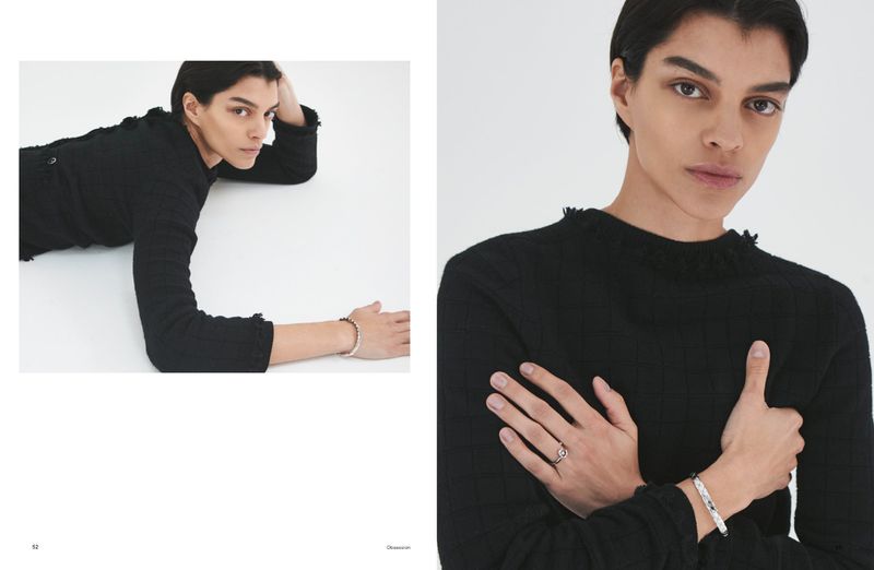 Model in a black textured knit top and silver jewellery posing against a plain white background in an editorial spread.