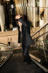 Man wearing a dark suit descending an escalator in a modern interior setting
