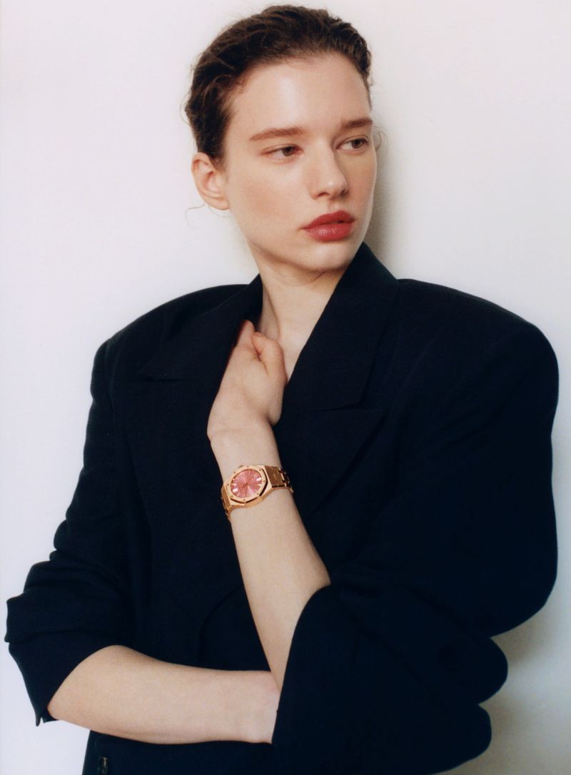 Model Sandra Murray posing in an oversized black blazer and rose gold wristwatch with a pink face against a white backdrop.