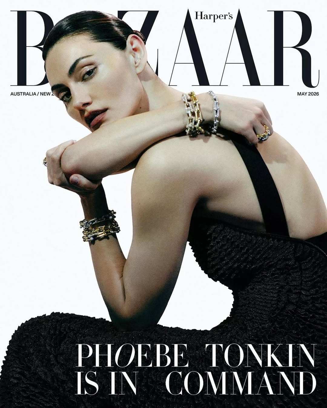 Phoebe Tonkin in a textured black backless dress wearing stacked chain bracelets on the Harper's Bazaar Australia cover.