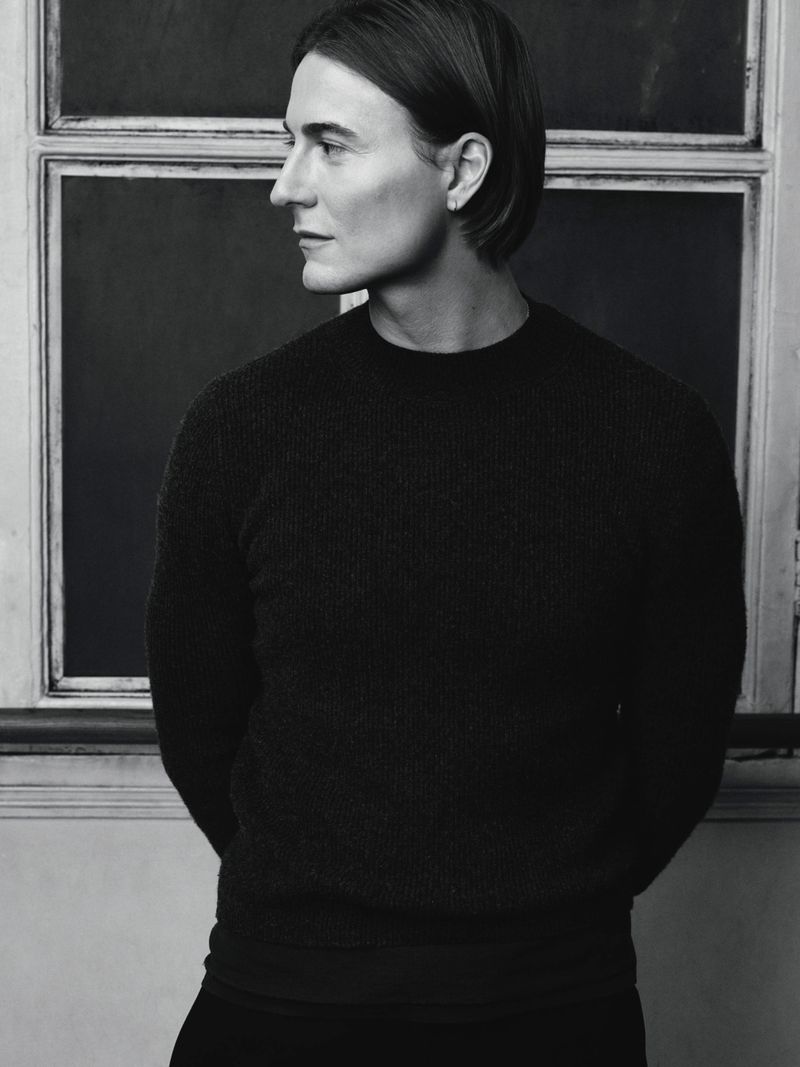 Monochrome portrait of Alain Paul in profile wearing a dark knit sweater against an interior window frame.