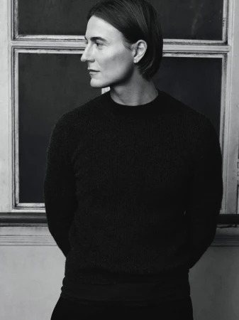 Monochrome portrait of Alain Paul in profile wearing a dark knit sweater against an interior window frame.