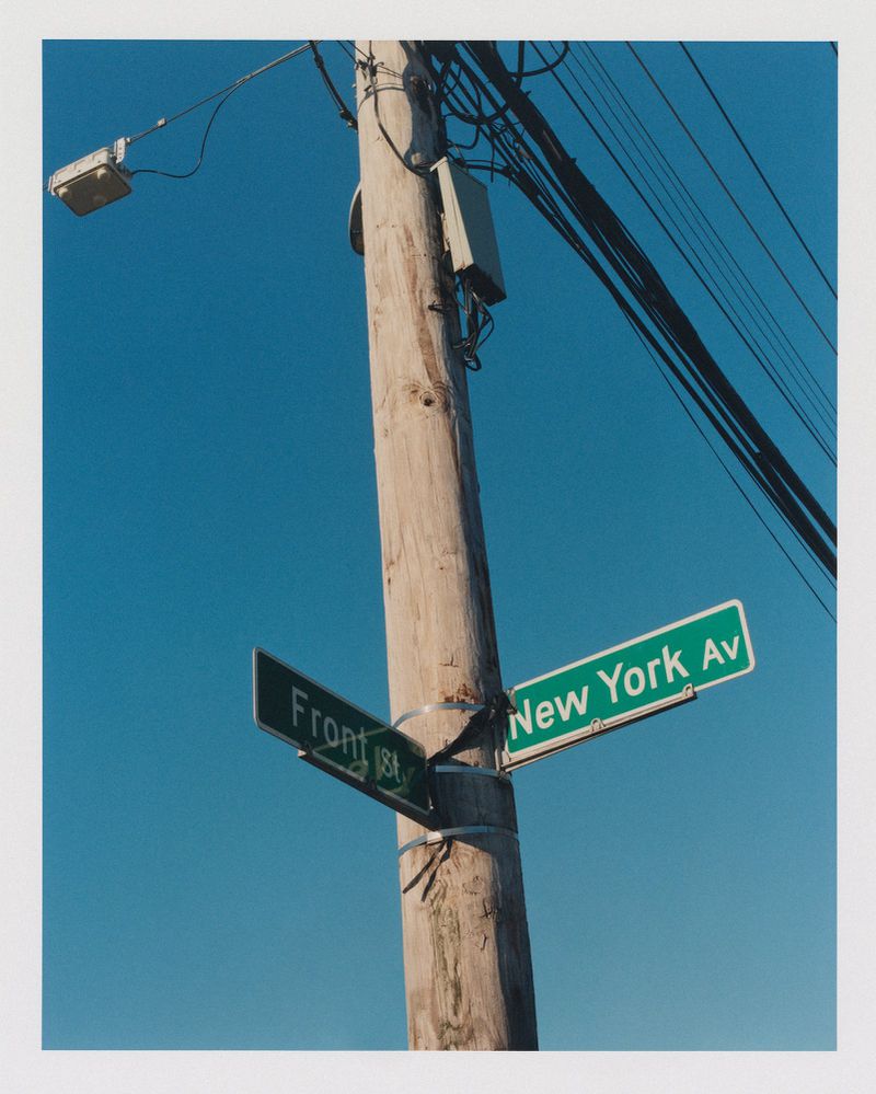Street sign for New York Avenue and Front Street attached to a telephone pole against a clear blue sky on a sunny day.