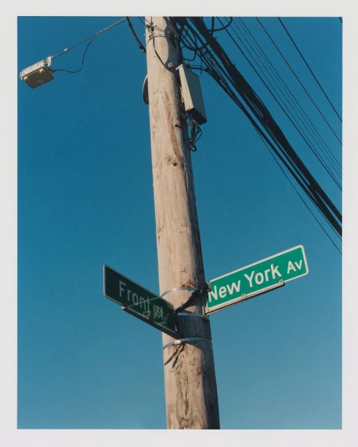 Street sign for New York Avenue and Front Street attached to a telephone pole against a clear blue sky on a sunny day.
