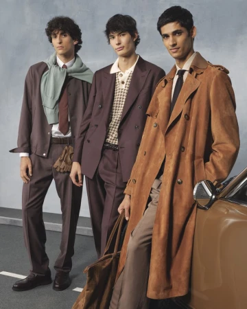 Three adult male fashion models pose next to a vintage car wearing a wool suit, polo shirt, trench coat and leather dress shoes.