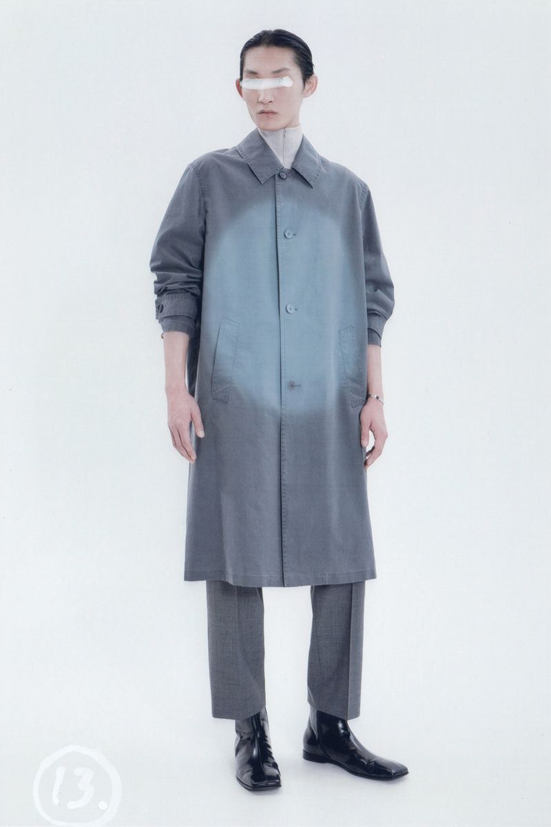 A full-length shot showcases an adult male model in a grey coat and trousers, paired with black boots, set against a bright white backdrop.