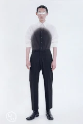 Model wearing a black and white gradient shirt, tailored trousers, and patent boots with eyes covered against a white background.