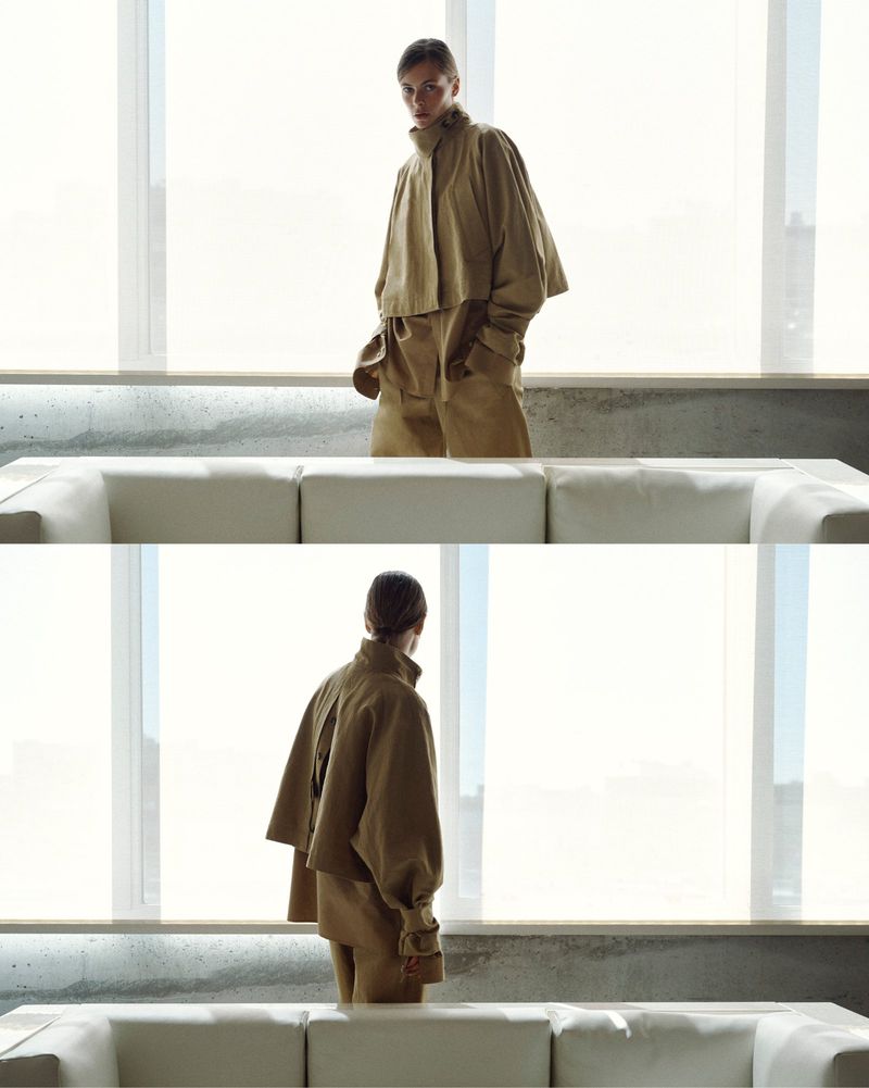 Model wearing a camel cropped jacket and matching trousers in a two-panel fashion lookbook portrait behind a white sofa.