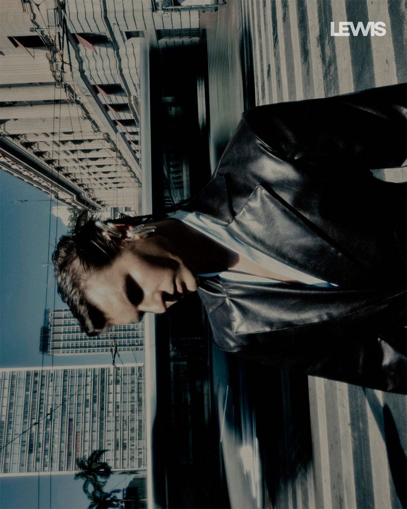 Model in black leather jacket outdoors on a city street shot from a high angle against buildings