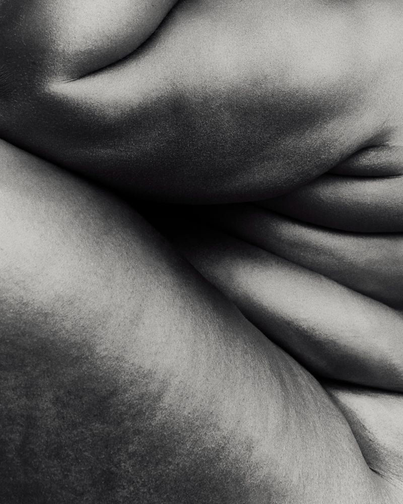 Monochrome close-up photograph of natural human skin folds and curved anatomical contours.