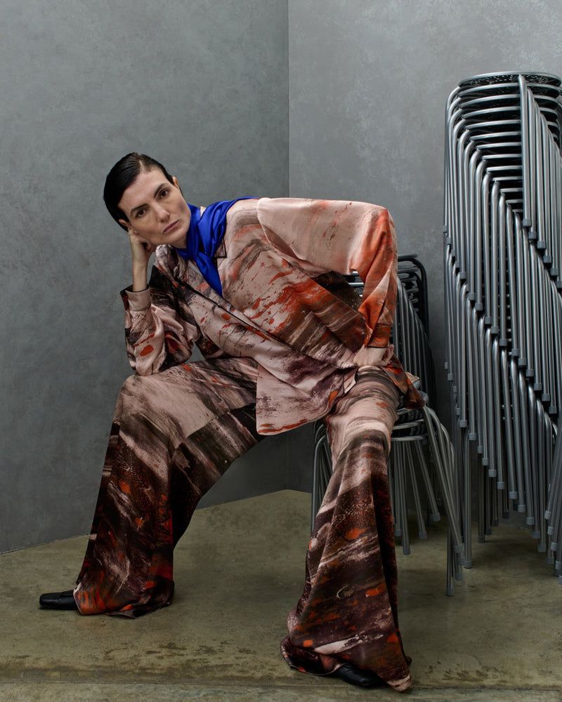 Model Eliana Weirich seated in an earthy brushstroke-printed matching suit and blue scarf for Roksanda Spring/Summer 26.