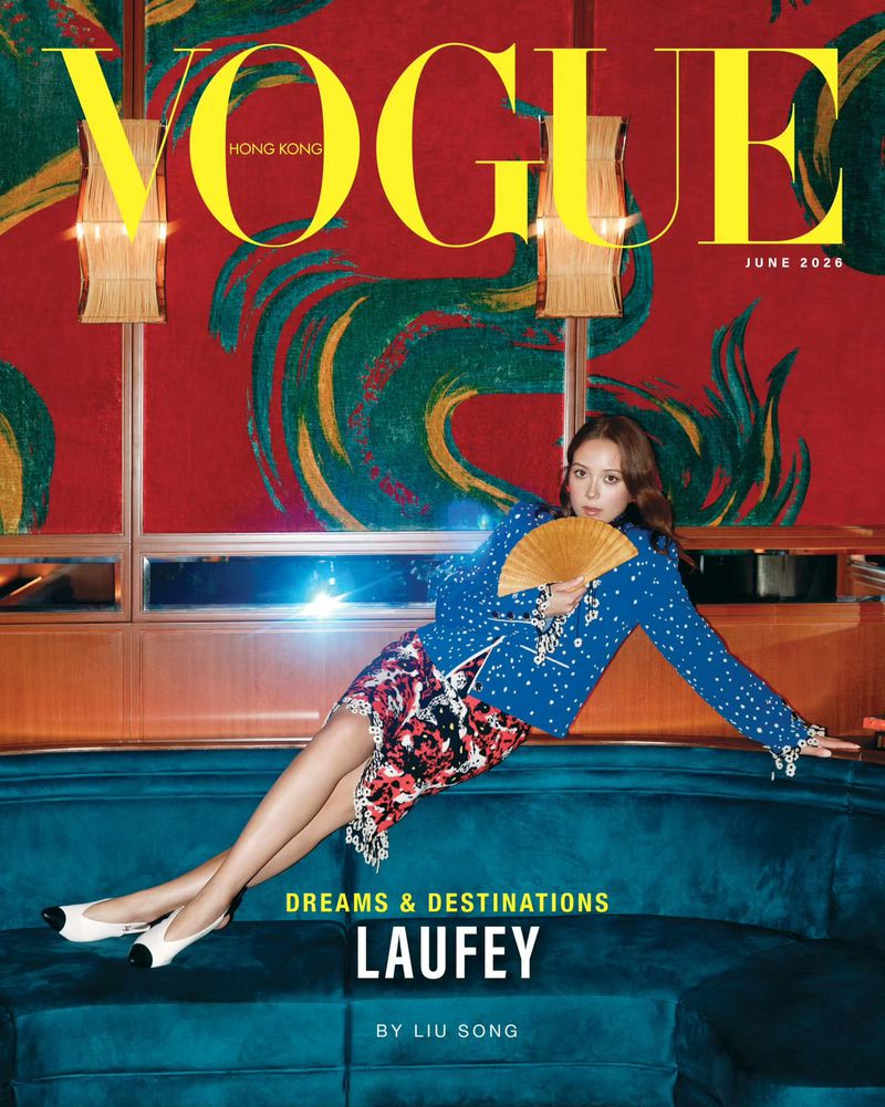 Laufey lounging across a teal velvet banquette holding a wooden hand fan on the Vogue Hong Kong June cover.