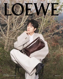Wang Yibo in a light blazer holding a brown leather bag outdoors for Loewe SS25