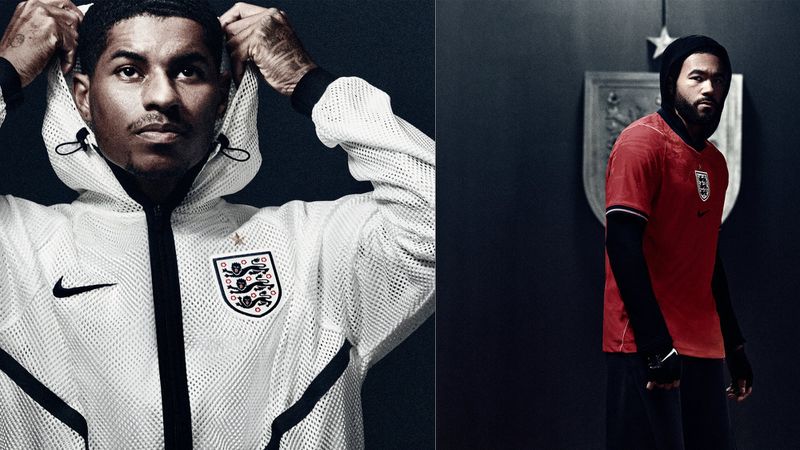 Marcus Rashford and another England athlete posing in Nike England soccer apparel against a dark studio backdrop.