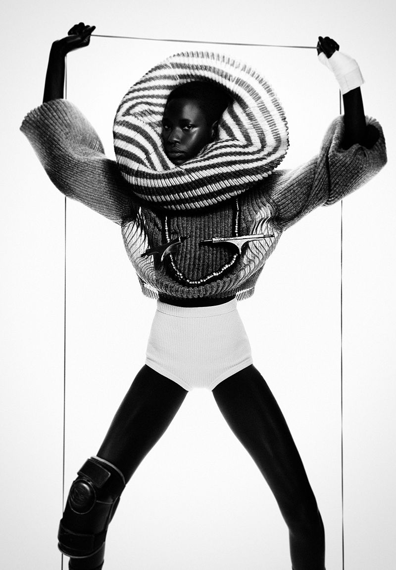 Model Awar Odhiang in a striped sculptural neckpiece and sweater against a white seamless backdrop for Dazed Magazine.