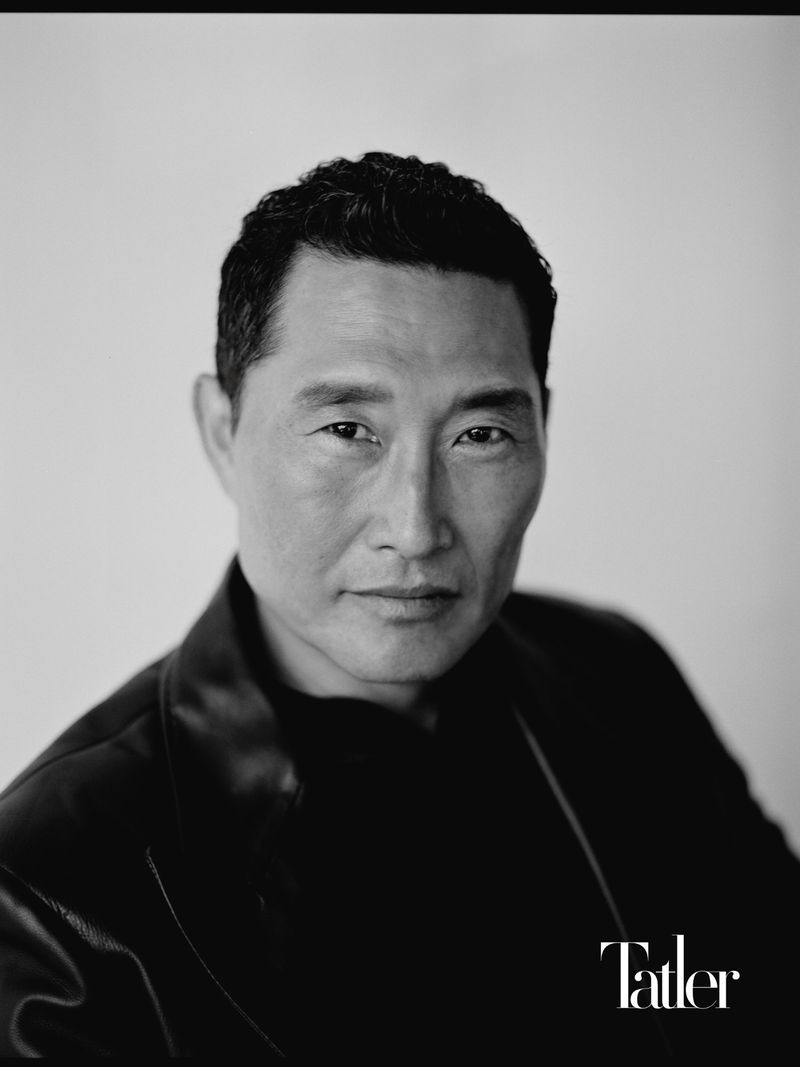 Black and white portrait of actor Daniel Dae Kim wearing a dark leather jacket against a light studio backdrop.