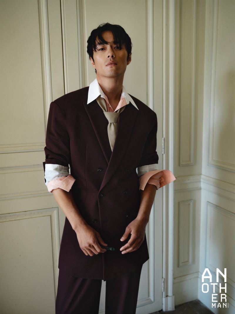 Model Zhao Lei wearing a dark brown double-breasted suit inside a room with paneled doors.